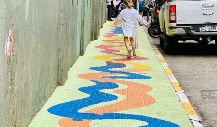 Vereda pintada con un juego de zig zag: un niño camina sobre la línea naranja 